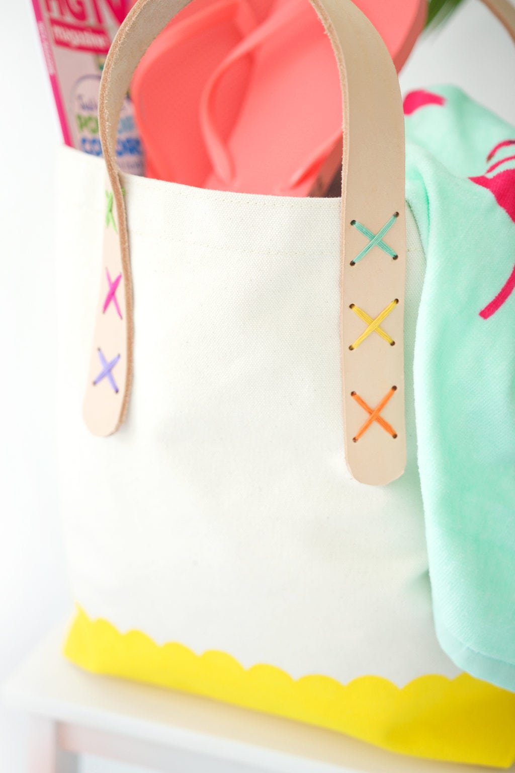 Transform a regular canvas tote bag into a DIY Leather Strap Canvas Tote Bag with the addition of leather and a few basic crafting supplies.