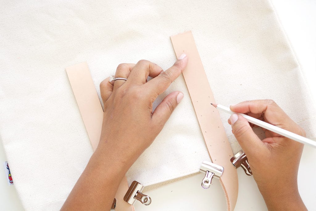 Transform a regular canvas tote bag into a DIY Leather Strap Canvas Tote Bag with the addition of leather and a few basic crafting supplies.