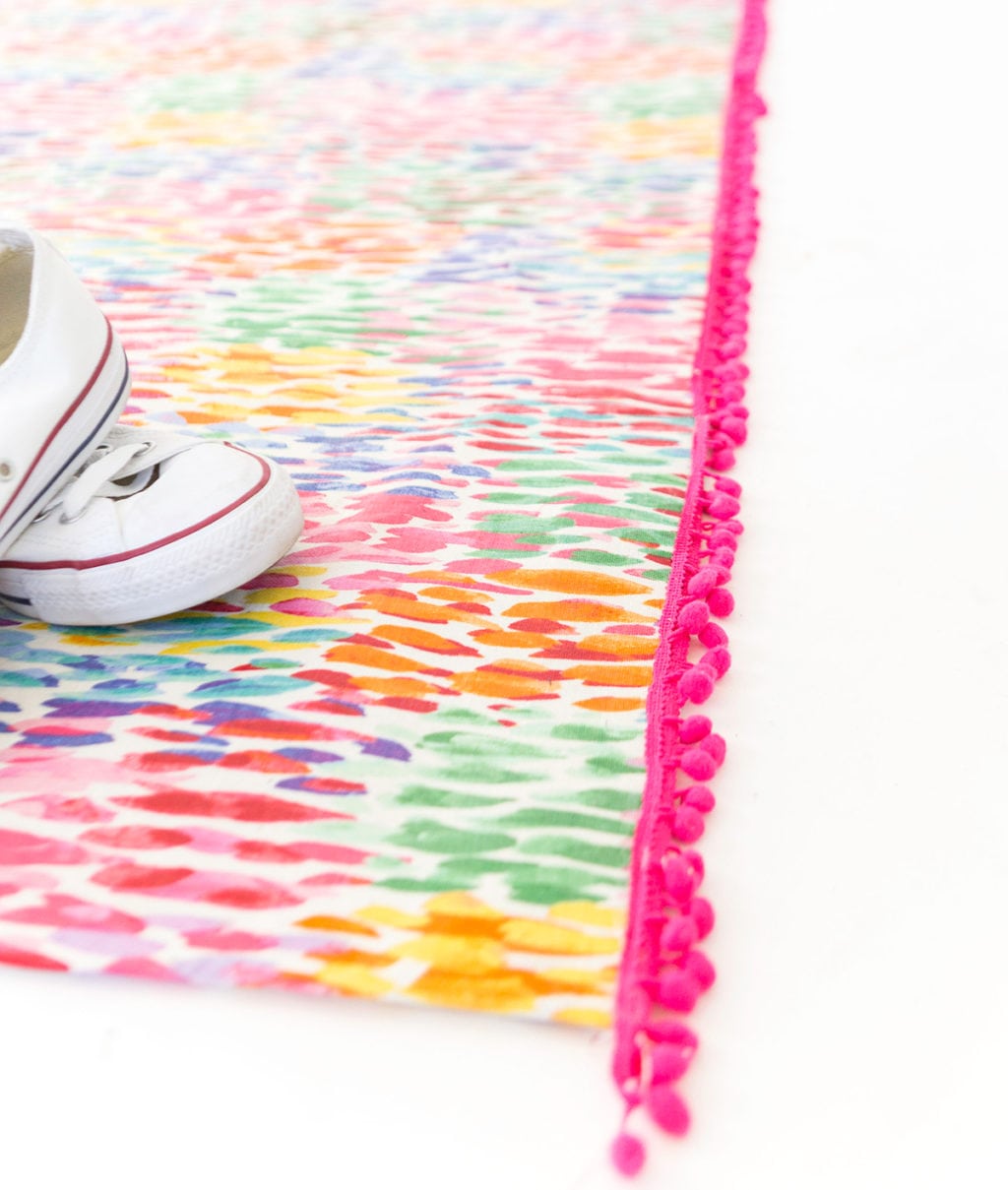 Large area rugs can be pricey! Follow this tutorial on how to turn a regular piece of fabric into a DIY Mod Podge Fabric Rug. It's totally customizable and afforable. 