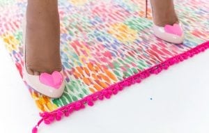Large area rugs can be pricey! Follow this tutorial on how to turn a regular piece of fabric into a DIY Mod Podge Fabric Rug. It's totally customizable and afforable.