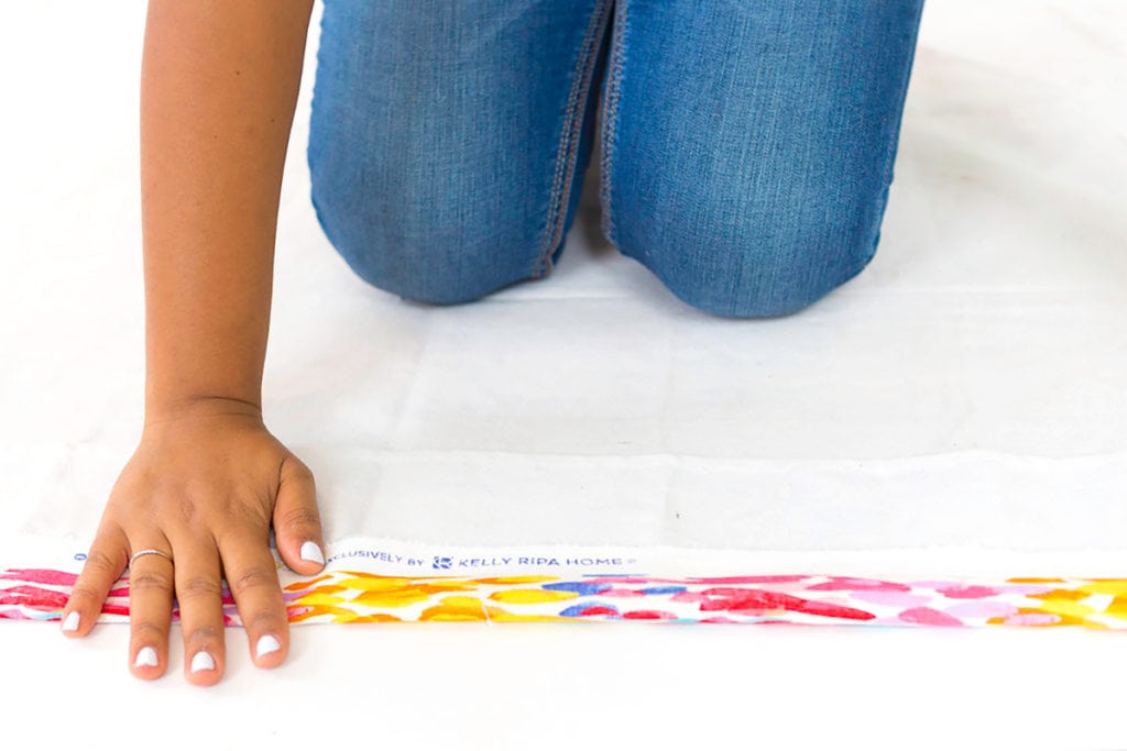 Large area rugs can be pricey! Follow this tutorial on how to turn a regular piece of fabric into a DIY Mod Podge Fabric Rug. It's totally customizable and afforable. 